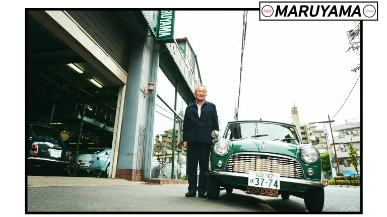 Kazuo Maruyama standing in front of his workshop next to a classic Mini. 