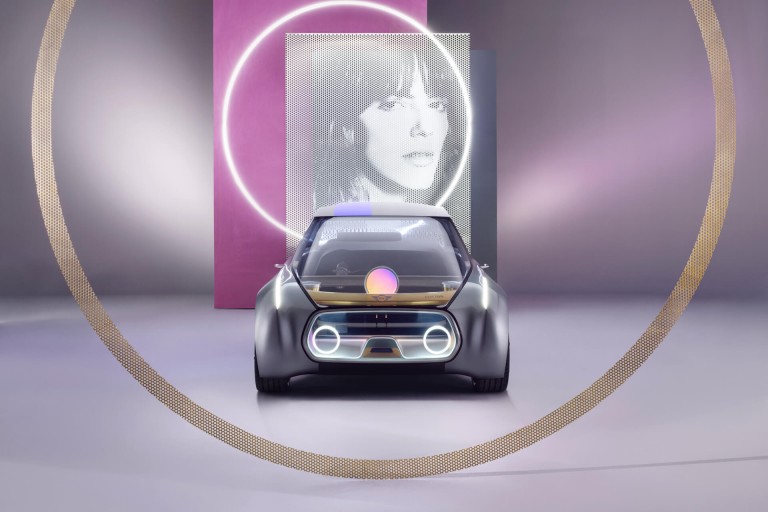 Photograph of a woman is pictured above a MINI VISION NEXT 100, front view.