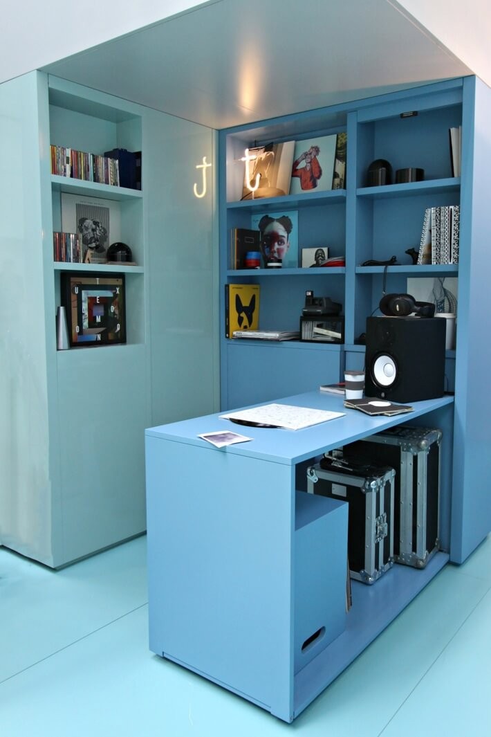 Blue shelving and storage units with vinyl records, a speaker, headphones, CDs and storage boxes