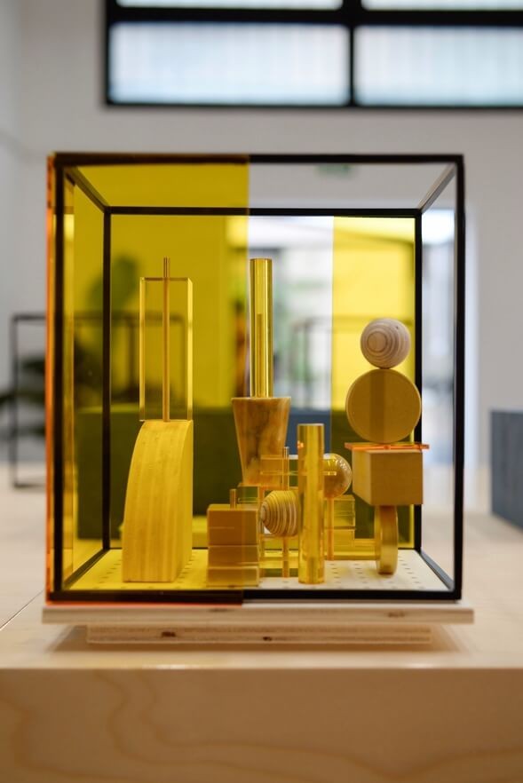 Close-up of a finished living space model featuring wooden blocks and  yellow screens in a black frame.