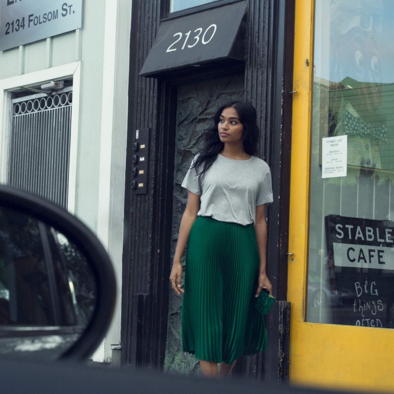 Through the window of a MINI, a woman is seen standing in front of building.