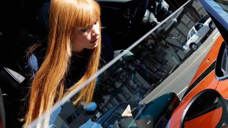 Young, red-haired woman gets into her Solaris Orange MINI Hatch.