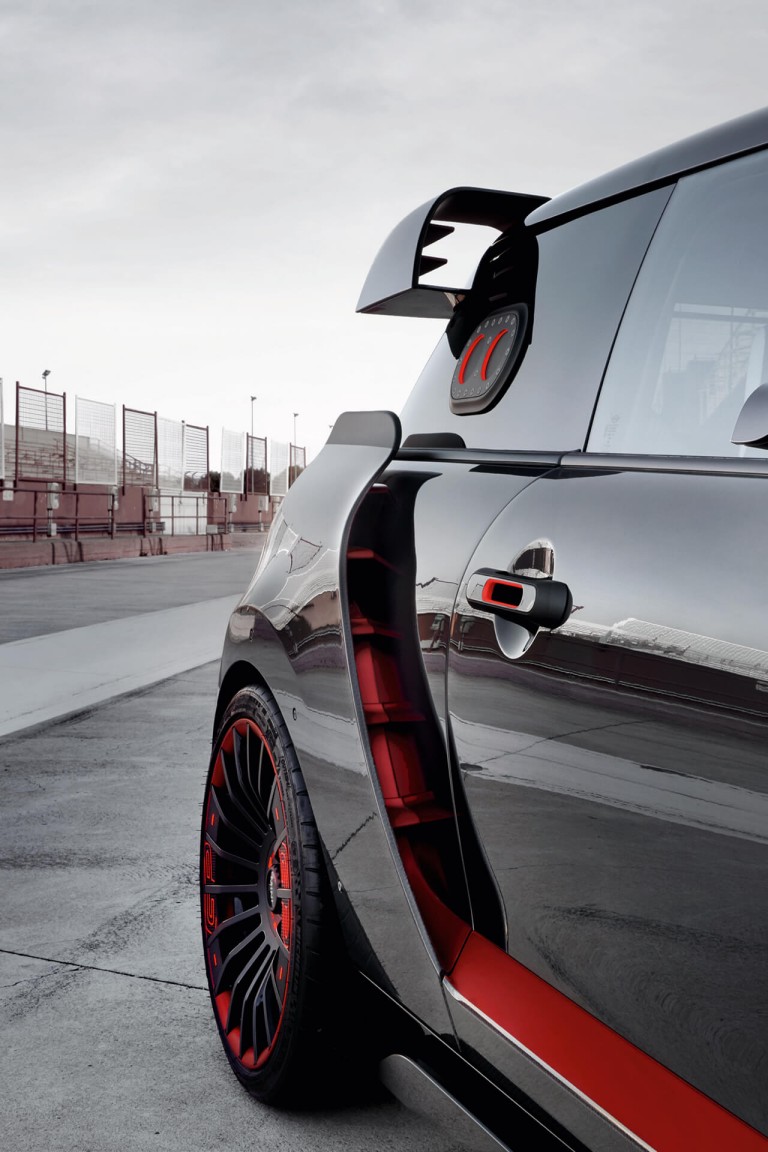 A red and black MINI John Cooper Works Concept drives past on a race track.