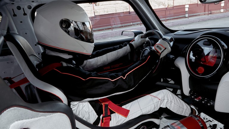 Interior shot: a man in racecar driving gear drives a MINI John Cooper Works Concept.