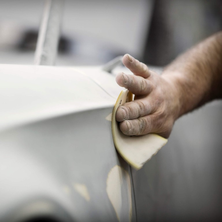 Factory worker puts the finishing touches on a new MINI Superleggera with sandpaper.
