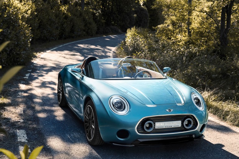 Sleek MINI Superleggera travels down a tree-lined country road, front view.