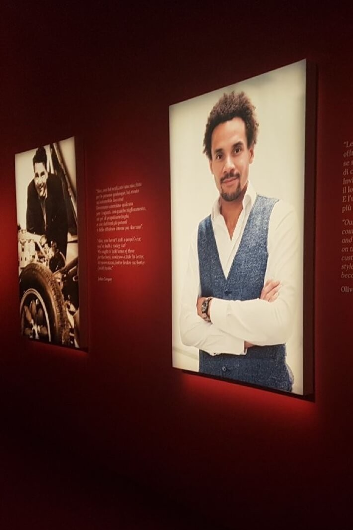Colour photo of MINI head designer, Oliver Heilmer, is in the foreground on an exhibition wall. A sepia-tone photo of and quote from John Cooper is visible in the background.