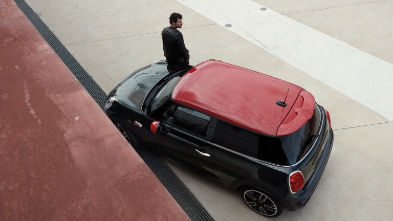 View from above of man sitting on the bonnet of a MINI John Cooper Works.  
