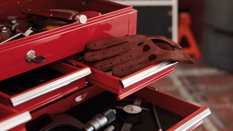 An open, motorsport tool box with MINI John Cooper Works gloves lying in one of the compartments.