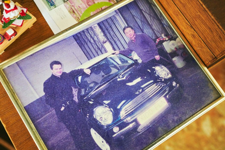 An old photograph of Kazuo Maruyama and John Cooper's son Michael (left), standing next to a MINI Cooper in the early 2000s.