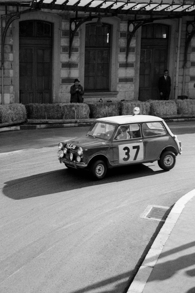 Photographers standing behind bales of straw capture the BMC Works Mini Cooper S on film at the 1965 Monte Carlo Rally.