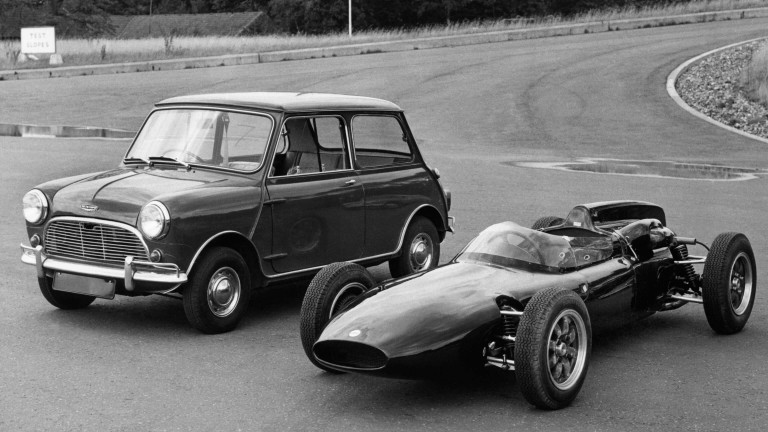 Vintage Mini Cooper parked on asphalt beside a vintage Formula One race car.