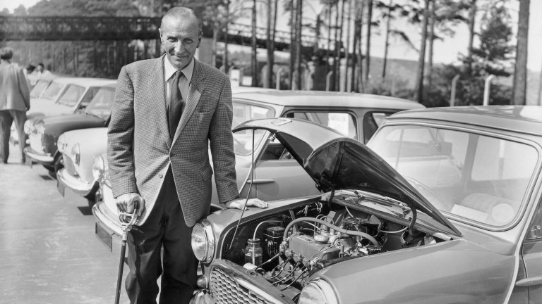 Sir Alec Issigonis standing in front of a Mini Morris-Minor with its bonnet up.