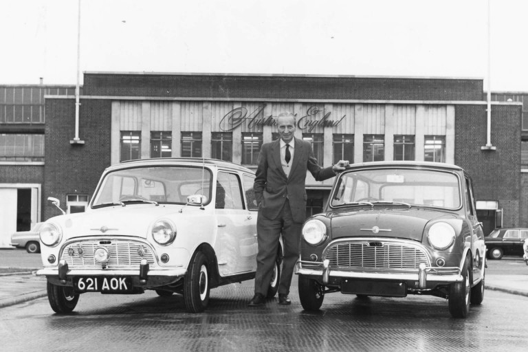 Sir Alec Issigonis standing in front of the Austin plant at Longbridge flanked by two Minis.