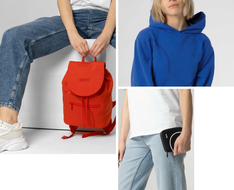 Three pieces of the new MINI Lifestyle Collection: a red backpack, a blue hoodie and a black wallet.
