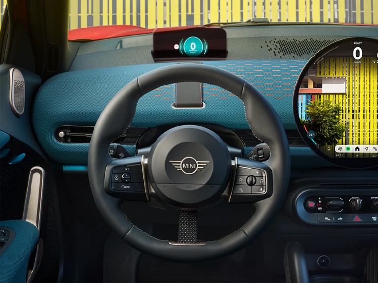 Close-up shot of the new MINI Aceman’s steering wheel and round OLED display, taken from the drivers’ point of view.