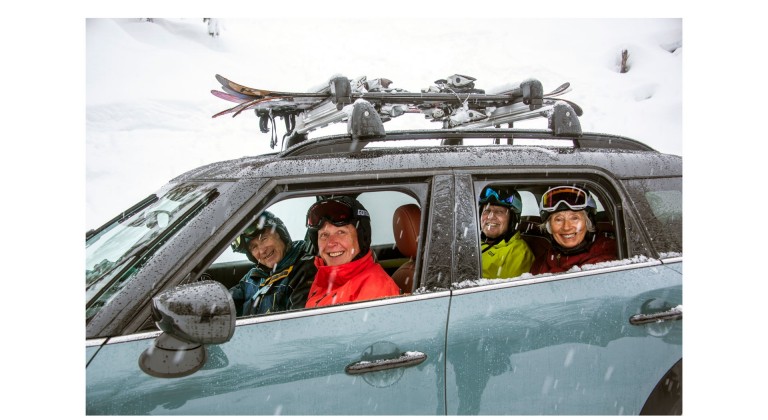 Picture of a MINI Countryman in a snowy landscape. The “Silver Sliders” ski crew  smiles out of the car window. 