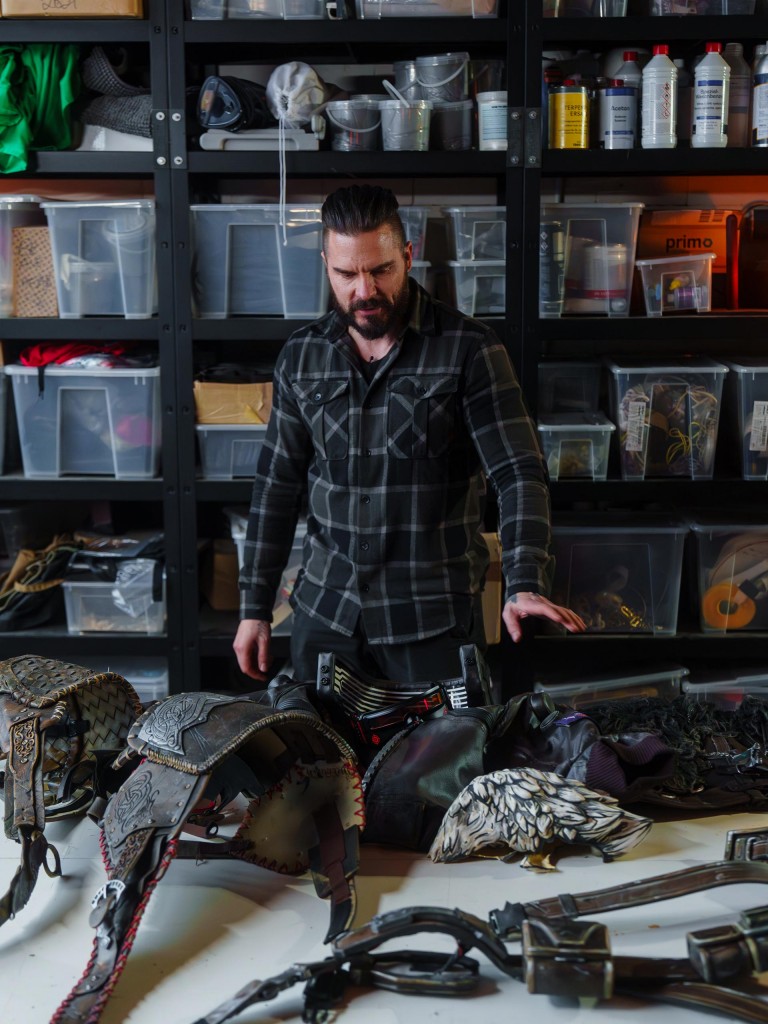Maul Cosplay standing at his work place with a table full of costume parts.