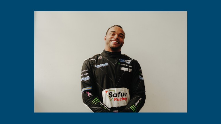 Race car driver and MINI host Nicolas Hamilton is wearing his racing suit and looks into the camera. 