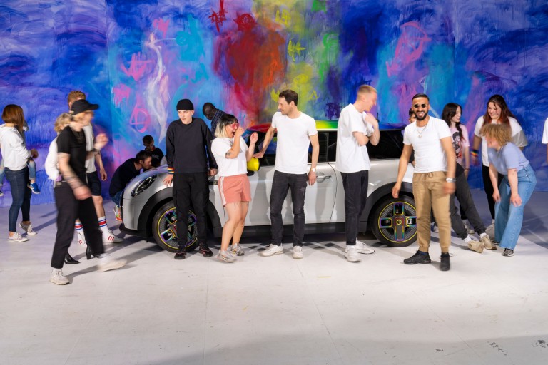 People posing with a MINI Cooper SE for MINI's ”We are all different, but pretty good together“ campaign