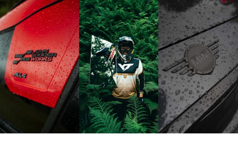 First picture: Close up of the red and black John Cooper Works ALL4 badge on the new MINI John Cooper Works Countryman. Second picture: In personalised gear and heavy-duty helmet, we see Vali’s upper half as she stands holding up a poster of herself and surrounded by thick green foliage. Third picture: Close up of water droplets on the black MINI badge on the black car bonnet.