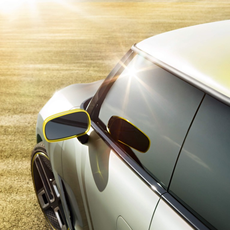 A silver MINI Electric Concept car with a yellow roof basks in the sun.