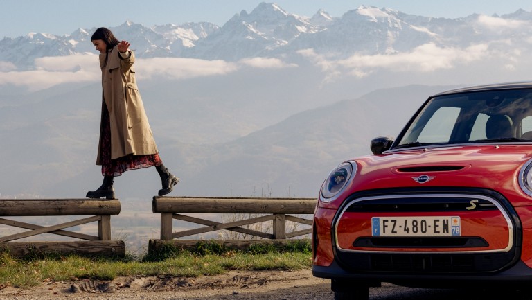 Image of a woman (author) and a MINI Cooper SE at Parking du Glacis in Grenoble, France. 