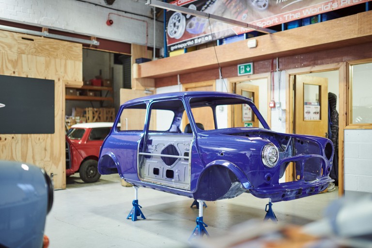 Side view of the jacked up and stripped car body of the MINI Recharged model in a workshop in Burnley.   