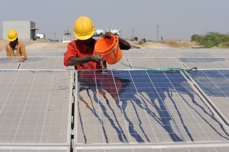 A photo of a worker cleaning dust off solar panels.