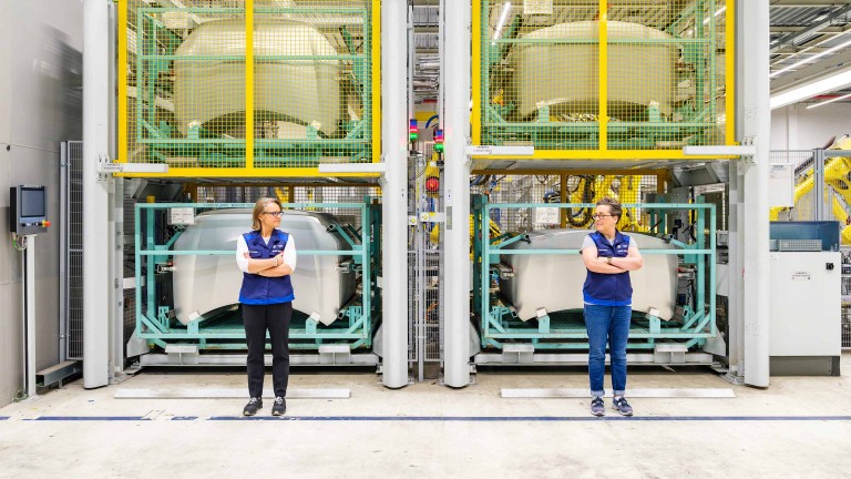 Arms crossed and wearing the plant’s mandatory vests, Plant Director and MINI Countryman Project Lead Sonja Hengstler share a glance as they stand in front of stored, unpainted car bonnets.